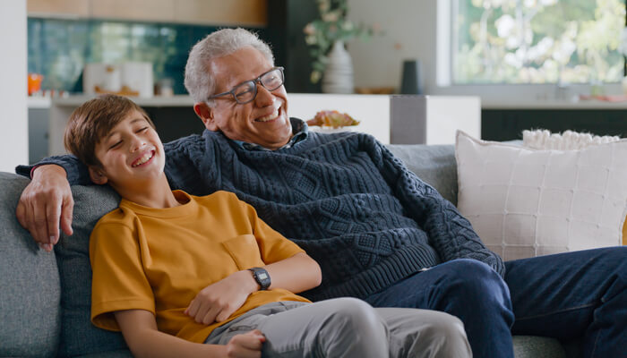 Grandfather and grandson smiling on a couch watching TV
