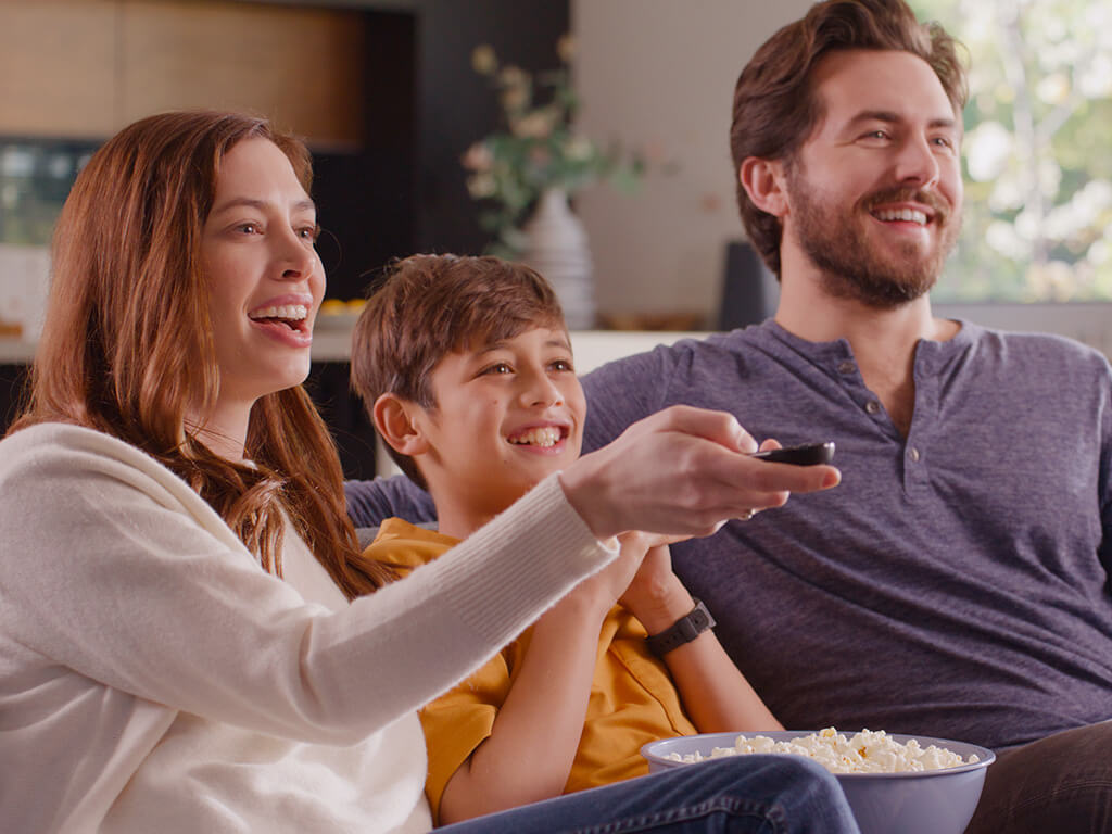 Family of three watching TV with popcorn